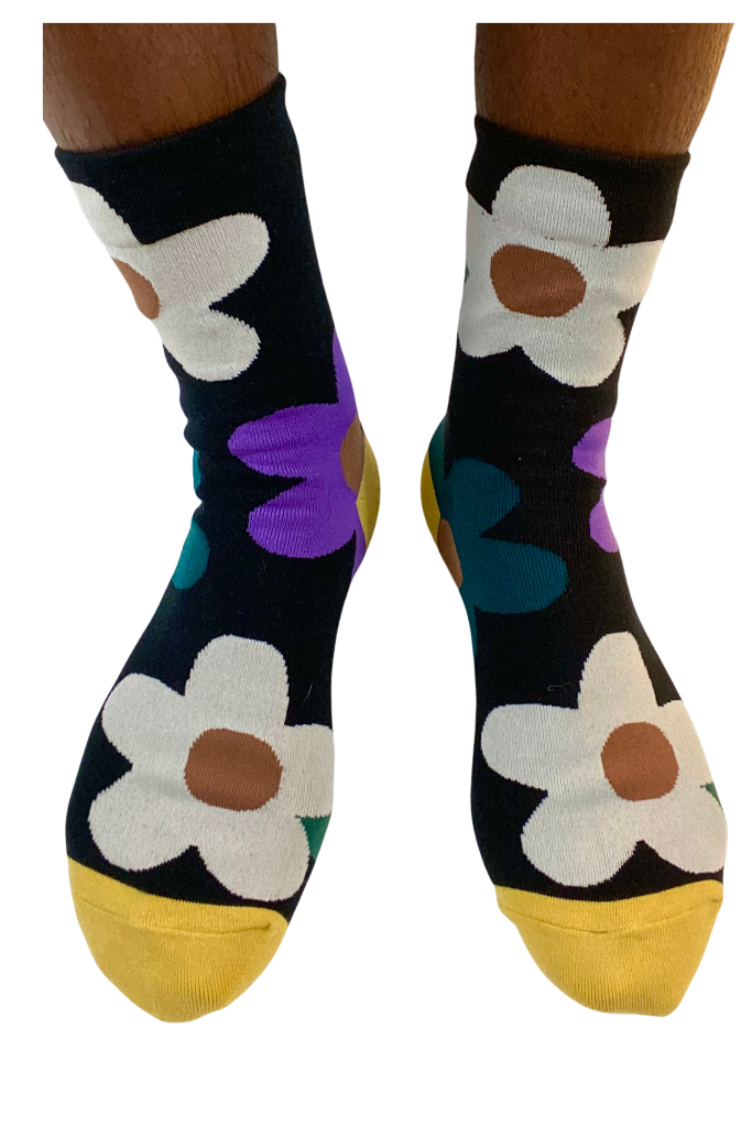 Women’s black crew socks with oversized daisy flowers and yellow toe accents – playful and vibrant sock design