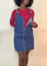 Women’s zip-front denim overall mini dress over a red long-sleeve top, partially unzipped — fall women’s denim dress outfit idea.