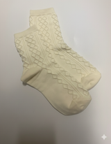 Pair of beige socks with textured pattern on a light gray background