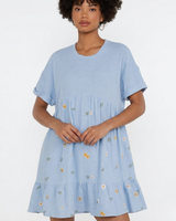 Woman wearing a light blue dress with floral embroidery on a white background