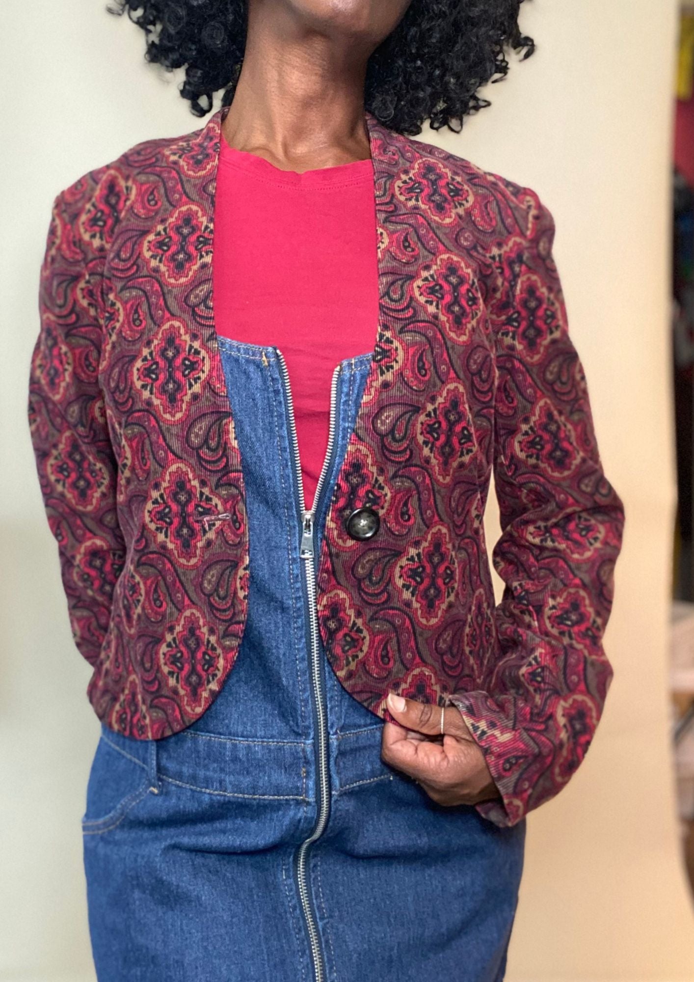 Woman wearing a zip-front denim mini dress layered with a red top and printed maroon blazer — chic fall outfit idea for women’s fashion.
