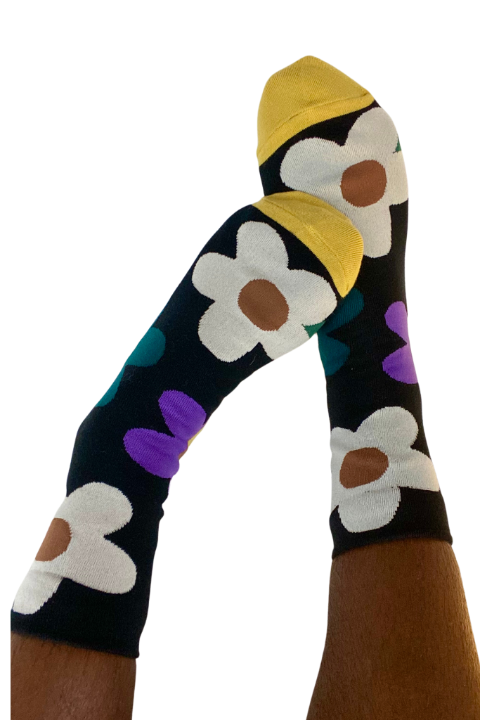 Women’s black crew socks with oversized daisy flowers and yellow toe accents – playful and vibrant sock design