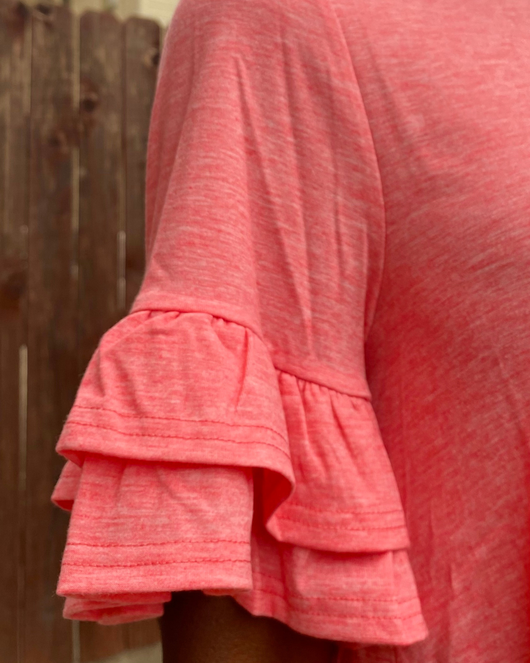 Close-up of the layered ruffle sleeve detail on a coral casual mini dress.