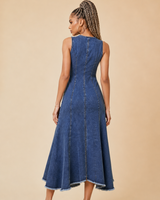 Back view of a women's dark rinse denim midi dress with front zipper detail, panel seams, and frayed hem, shown on a model against a beige studio background.