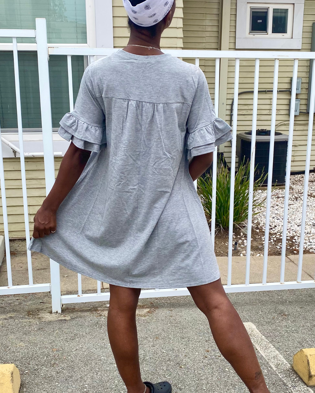 Back view of a woman wearing a gray ruffle sleeve t-shirt dress in a relaxed casual everyday style.