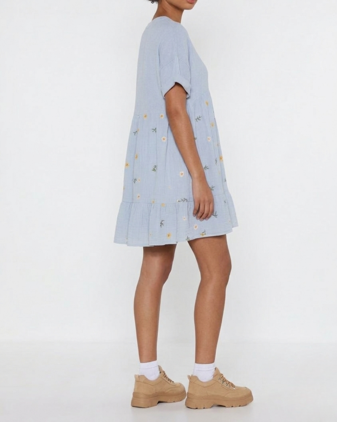 Person wearing a light blue dress with floral patterns on a white background