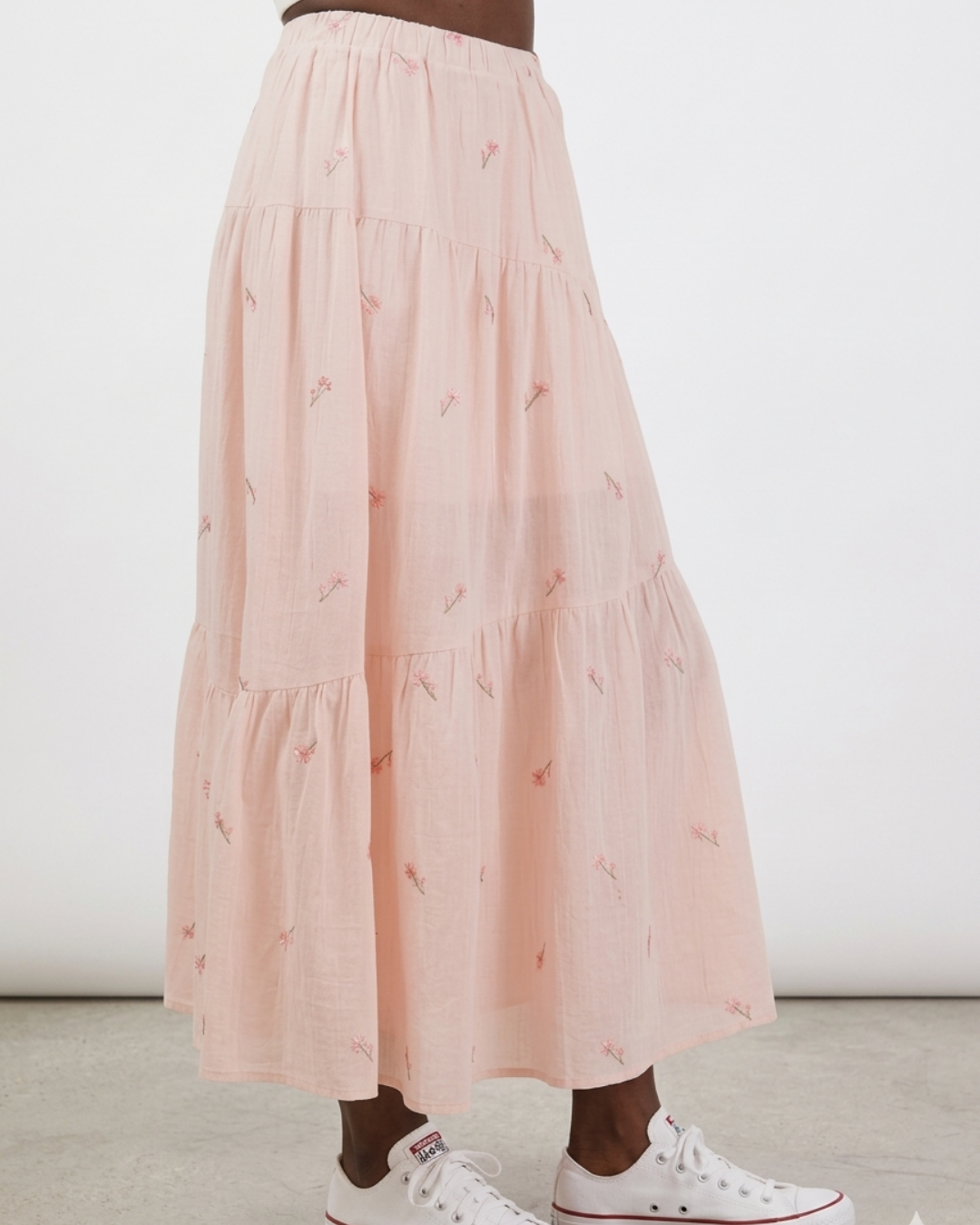 Person wearing a pink tiered skirt with small patterns on a plain background