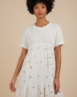 Woman wearing a white dress with floral patterns on a beige background