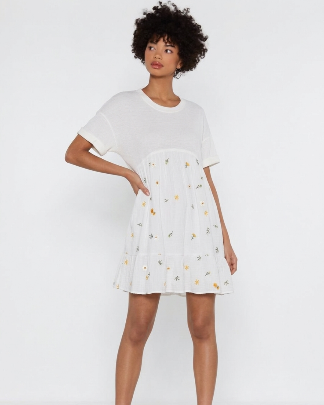 Woman wearing a white dress with floral pattern on a plain background