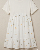 White dress with floral embroidery on a beige background