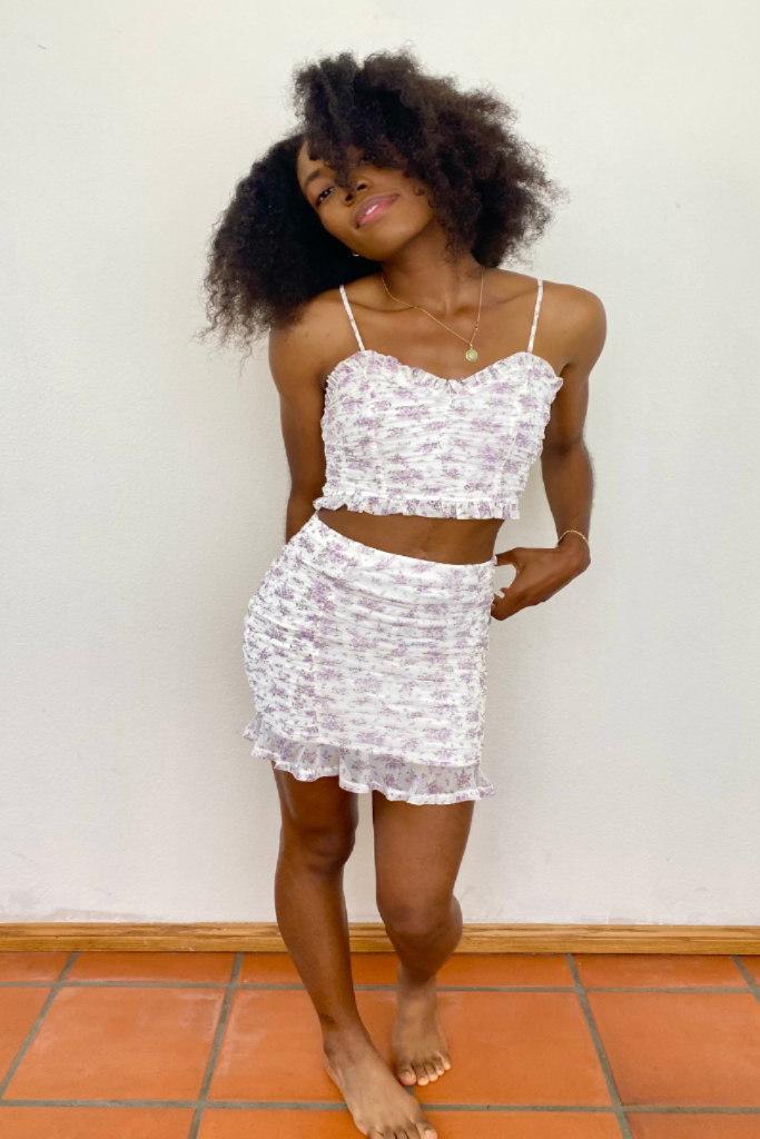 model wearing gold jewelry and a white cami skit set with delicate lavender floral print and ruffle trim - ruched two piece spring and summer outfit