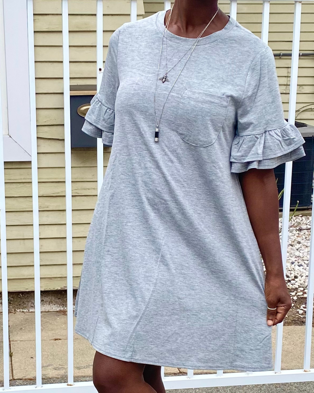 Woman wearing a gray ruffle sleeve t-shirt dress with a chest pocket in a casual boho everyday outfit.